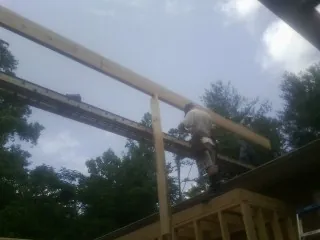 Carpenter setting a ridge beam over a new addition frame — Ice Dam Removal by Roofing Brothers in Hordville