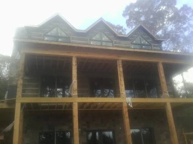 Dormers and porch framing on a large log home under construction — Roof Coating work by our crew in Hordville