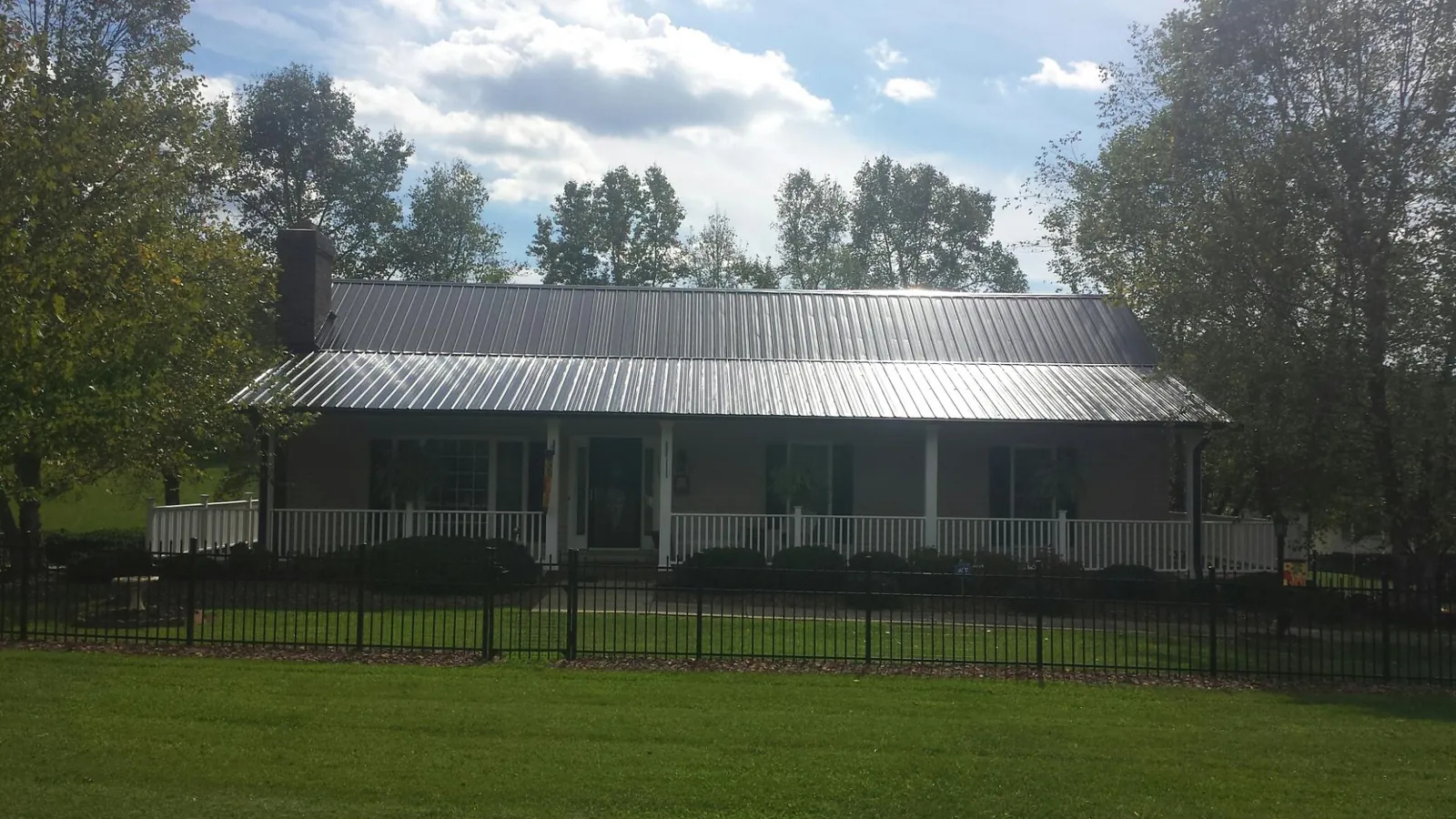Gray metal roof on a brick ranch with a full width front porch — Gutter Guard Installation work by our crew in Hordville