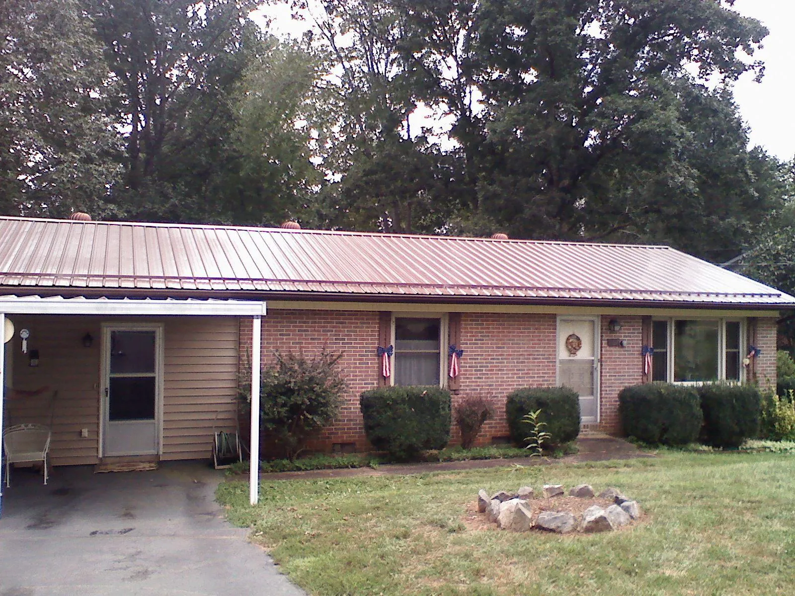 Bronze metal roof and carport on a brick ranch home — Roof Repair work by our crew in Hordville