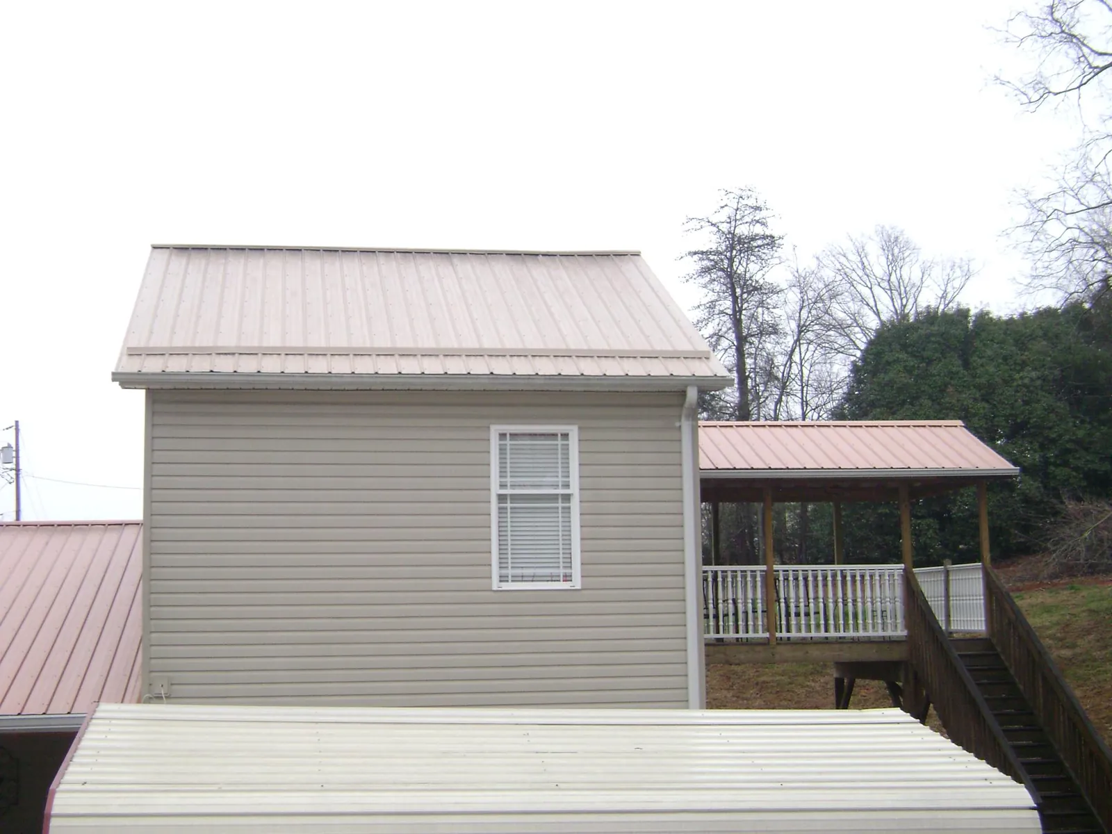 Tan metal roofs on a two story addition and attached porch, from a Roof Replacement job in Hordville