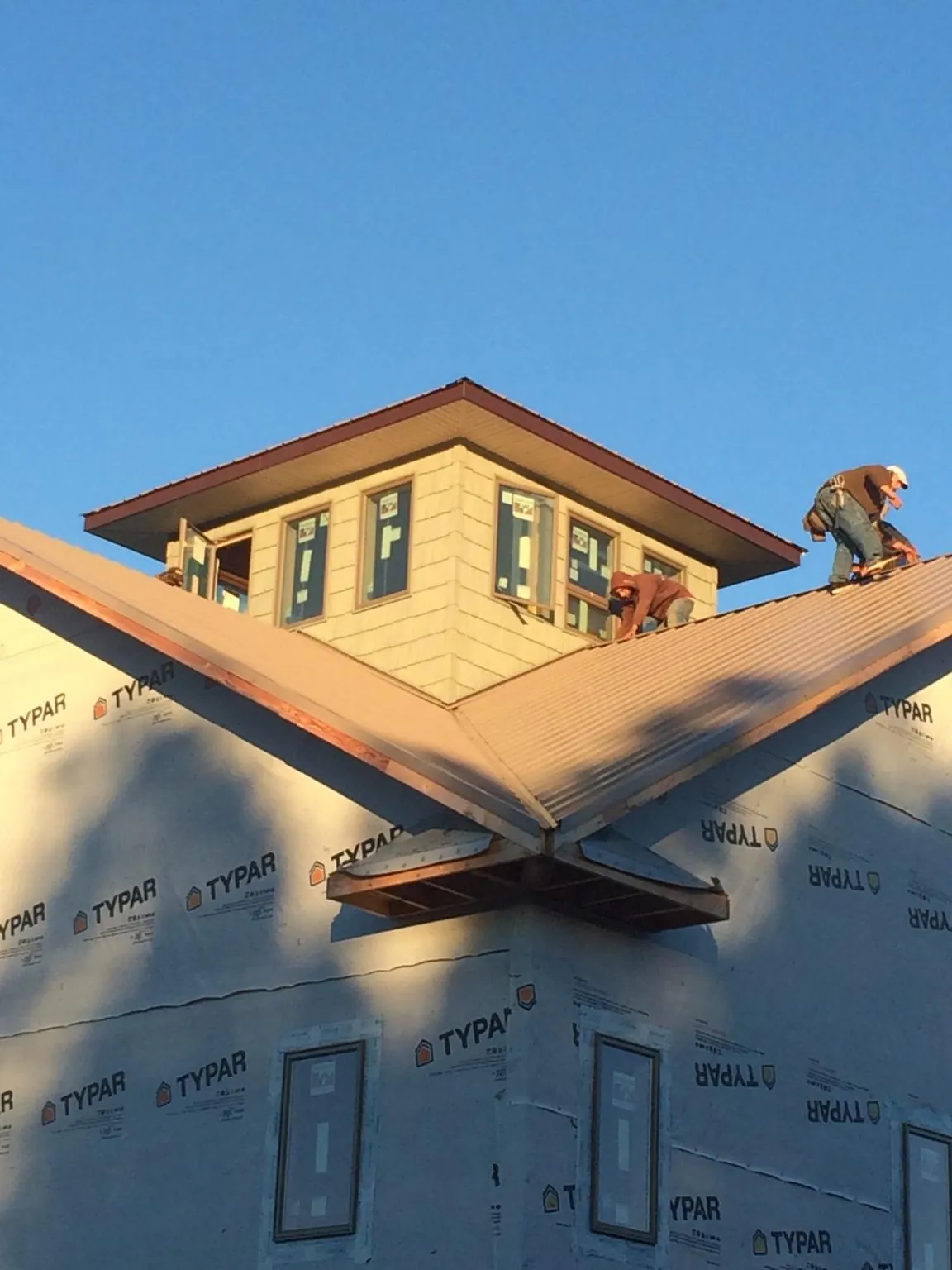 Roofers working around a rooftop cupola on a new metal roof at sunset — Roof Waterproofing in Hordville by Roofing Brothers